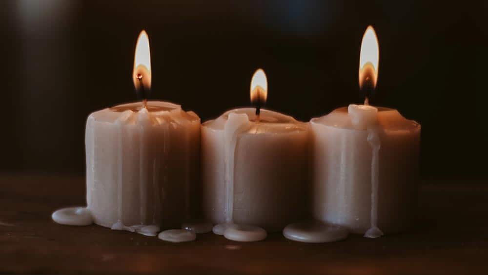 Drie brandende kaarsen naast elkaar.