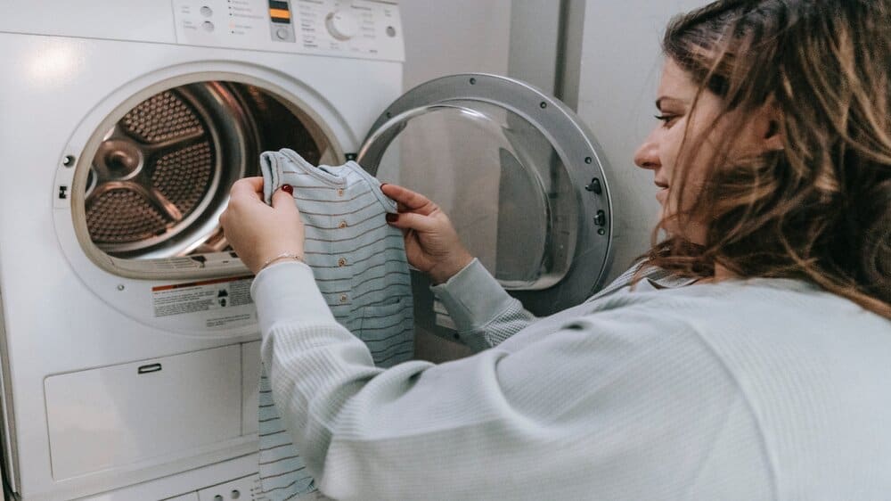 Een vrouw haalt wasgoed uit een droger.