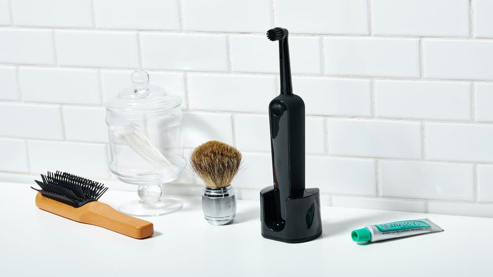 Zwarte elektrische tandenborstel met verschillende verzorgingsproducten.