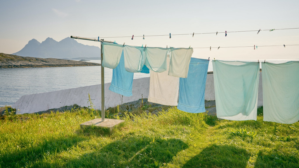 Lakens, handdoeken en kussenslopen aan twee waslijnen bij een meer met bergen op de achtergrond