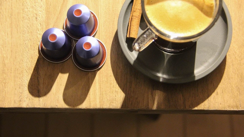 Kopje koffie met 3 paarse Nespresso cups ernaast