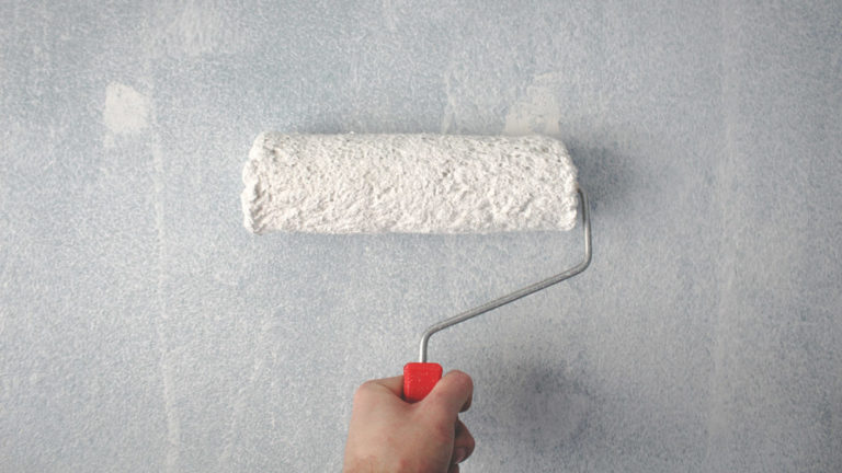verfroller met witte verf schildert muur