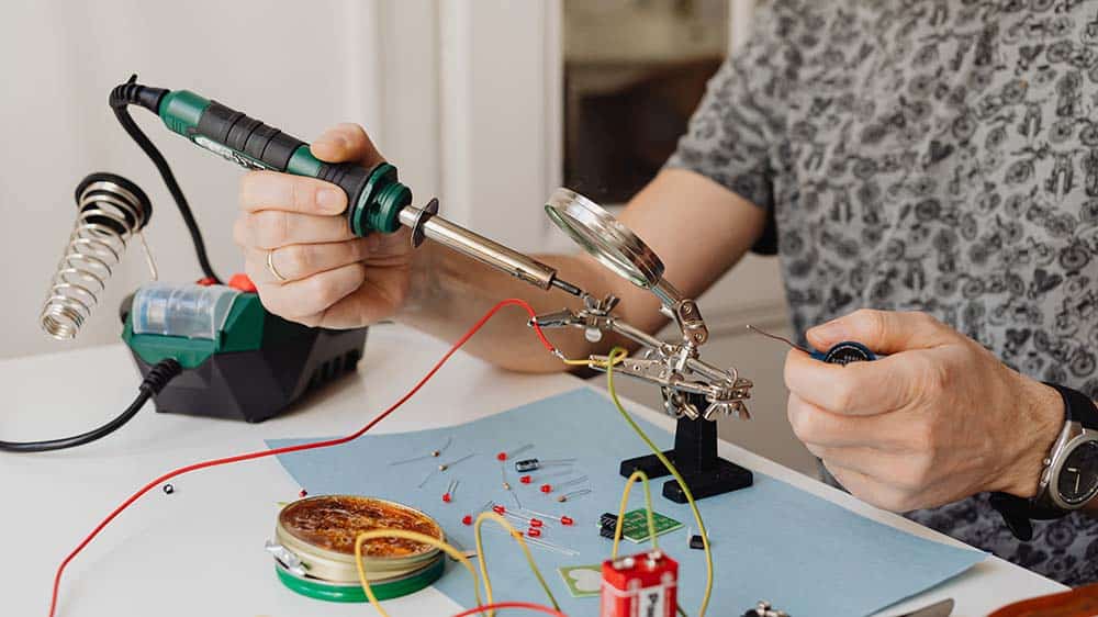 Man soldeert elektronica aan elkaar met een soldeerbout.
