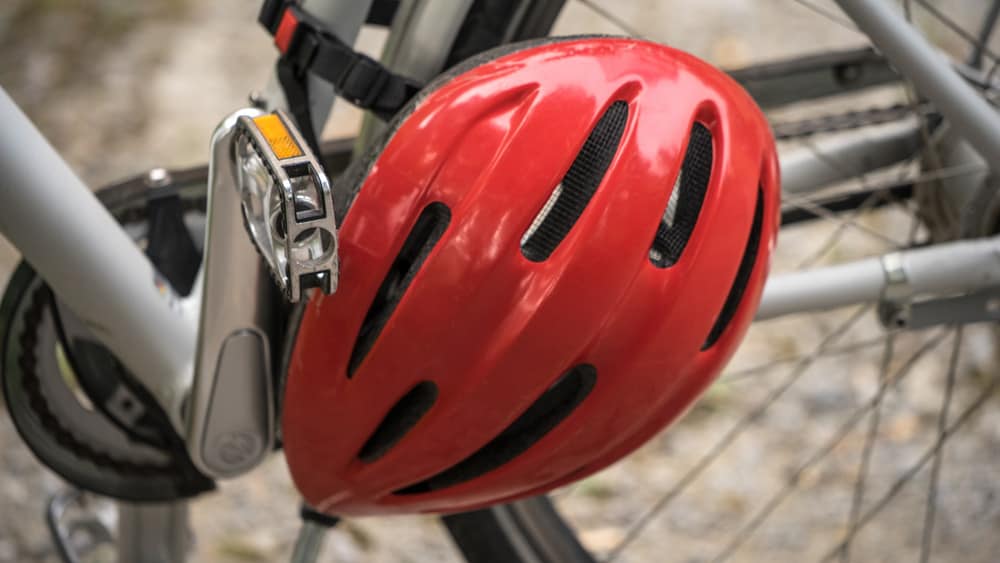 Een rode fietshelm hangt aan een fiets.