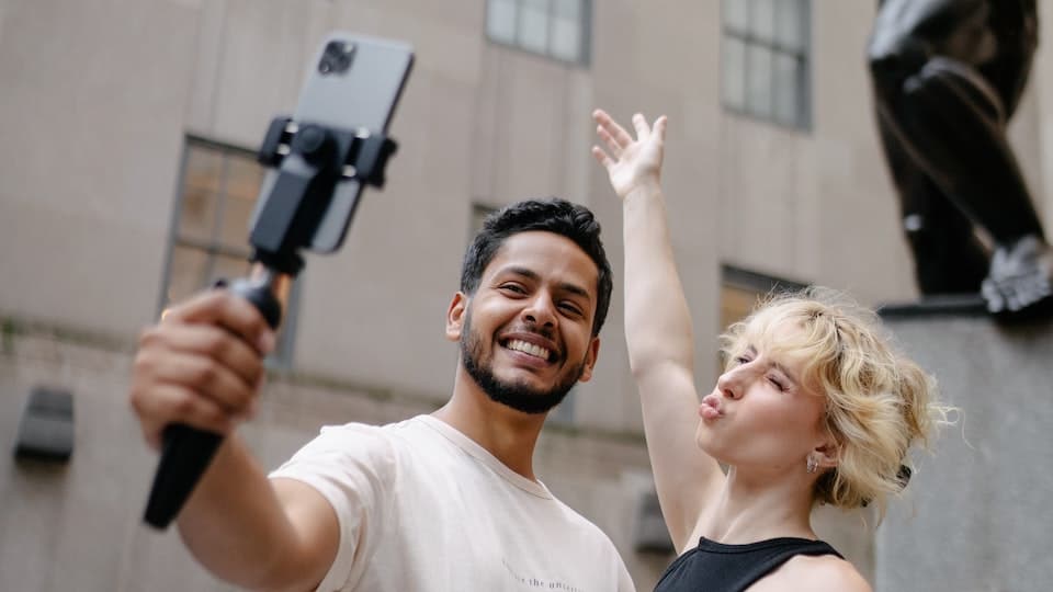 twee mensen maken een selfie met een selfiestick voor een standbeeld