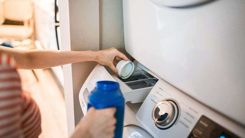 Vrouw giet wasmiddel in een wasmachine