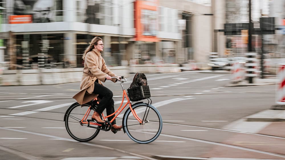 Vrouw fietst op transportfiets in de stad