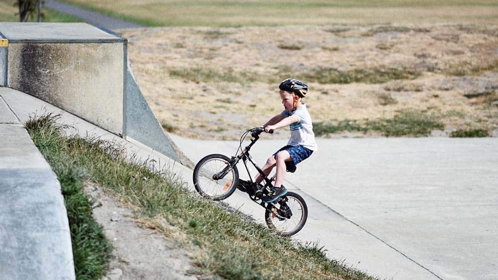 Jongetje fietst helling op met een kinderfiets