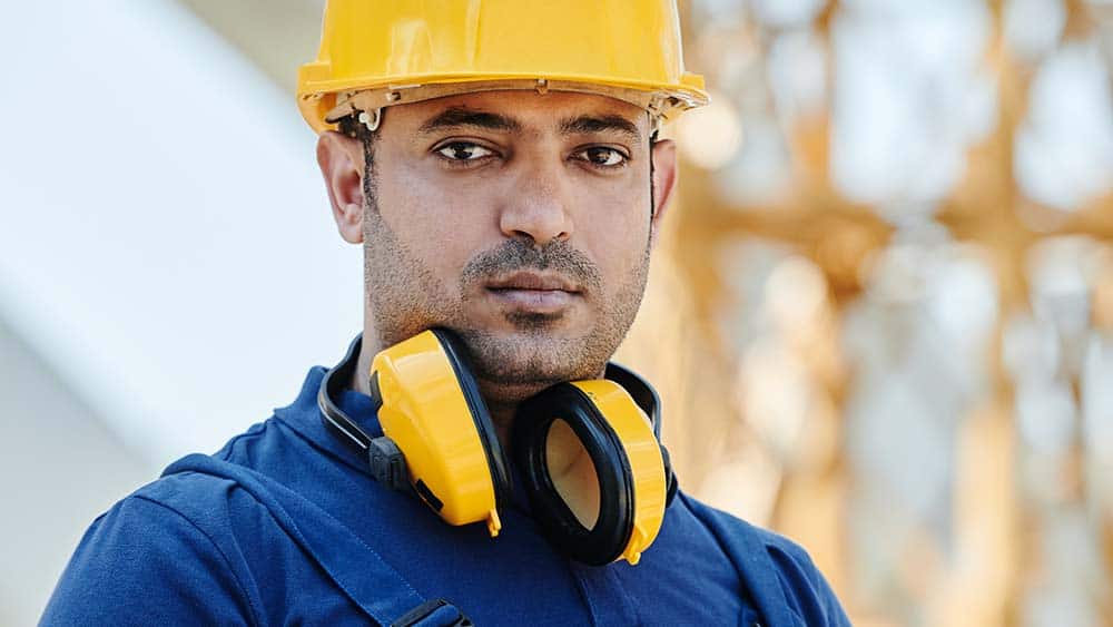 Een bouwvakker met een gele helm en gehoorbescherming