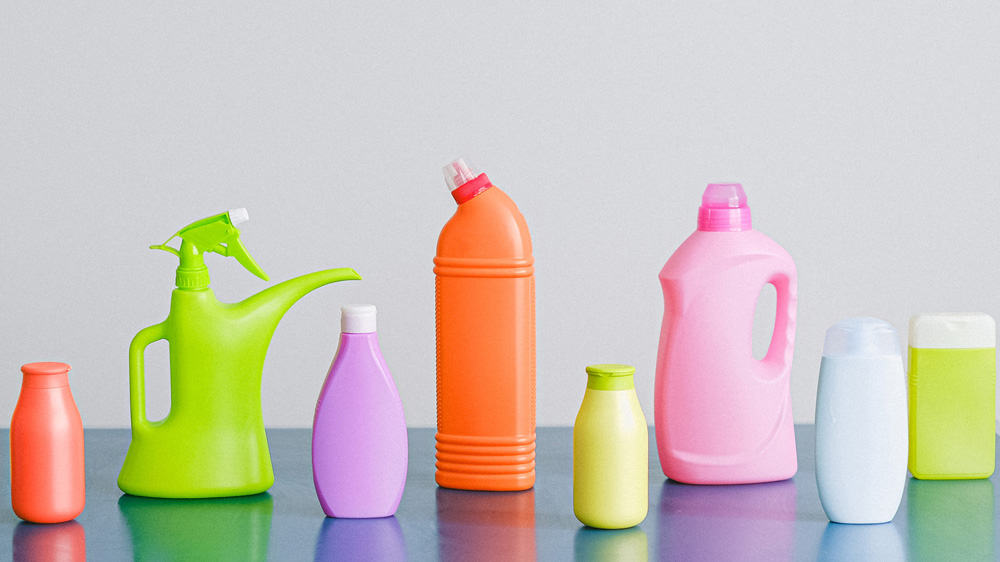 Gekleurde flessen wasmiddel en andere schoonmaakmiddelen staan naast elkaar op een tafel