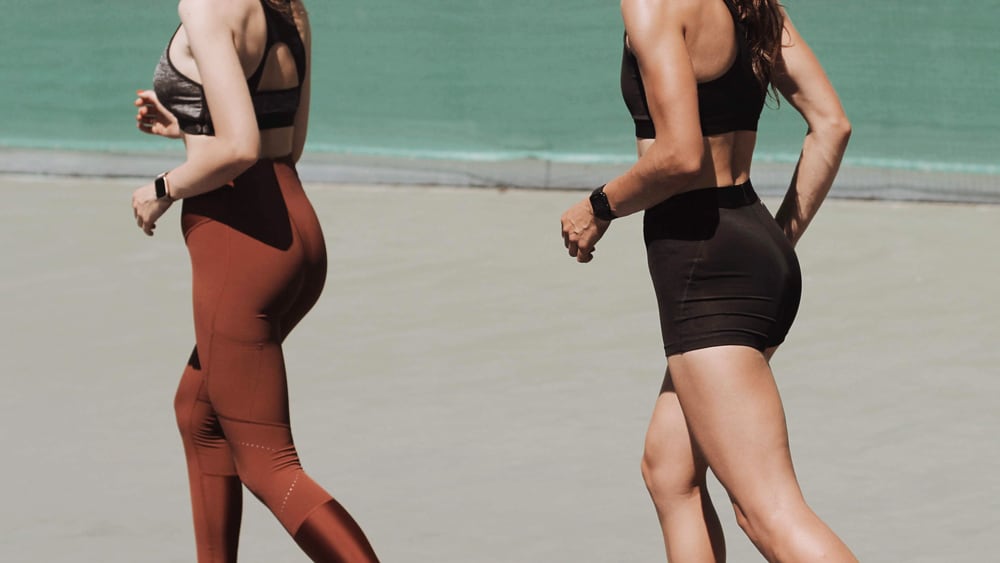 Twee joggende vrouwen met hardloophorloges om.