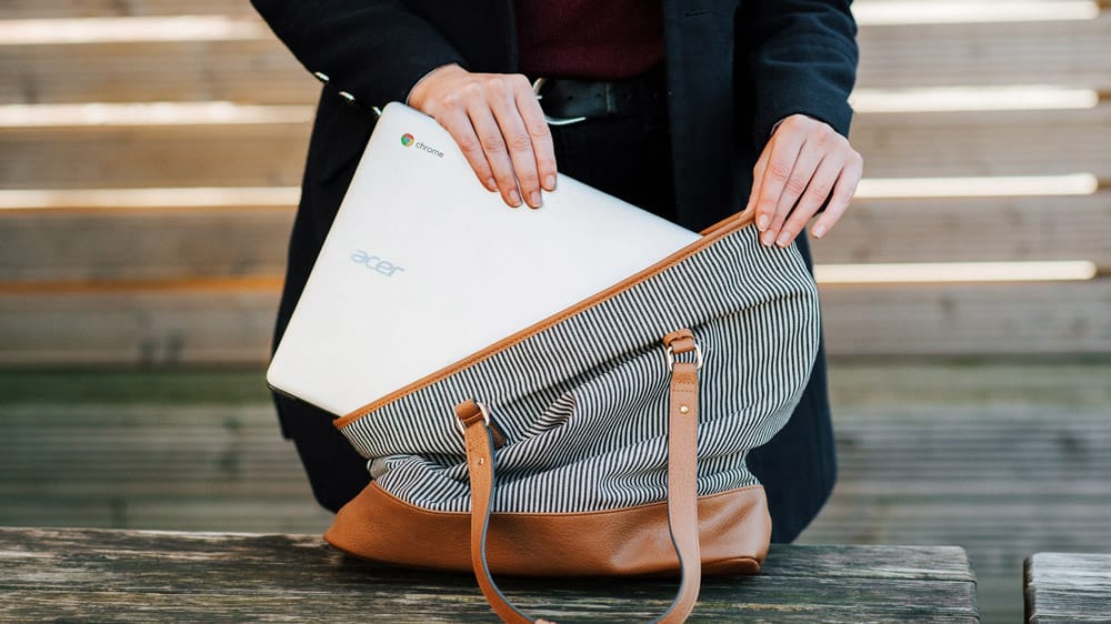 Een persoon stopt een Chromebook in een gestreepte tas