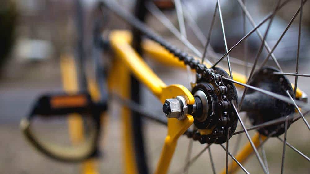 Een close-up van een fietsketting op een gele fiets