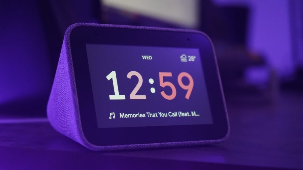 Een wekkerradio met cijfers op het scherm in een paars verlichte kamer