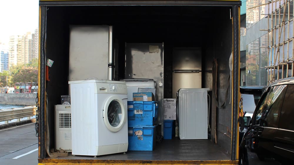 Een wasmachine in een vrachtwagen tussen kratten en verhuisdozen