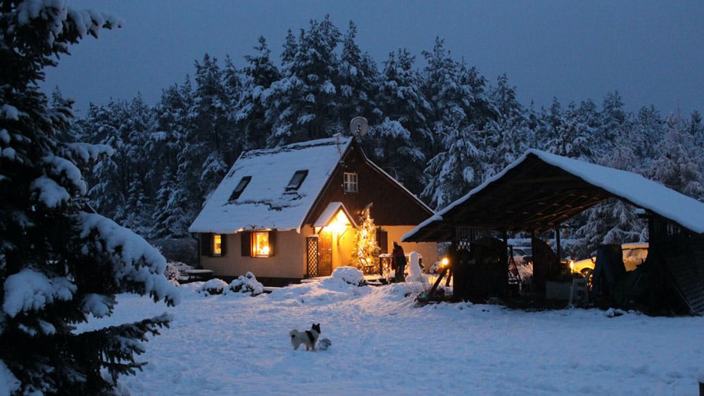 Een verlicht huisje in een sneeuwlandschap