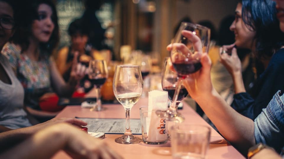 mensen zitten aan een lange tafel en drinken wijn
