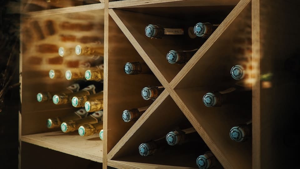 wijn en bier liggen in een houten rek