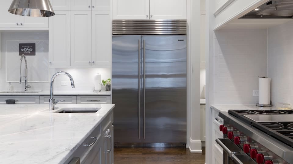 Een Amerikaanse koelkast staat in een witte ruime keuken
